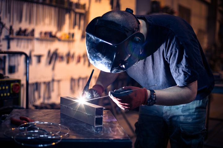 Employee welding aluminum using TIG welder in workshop