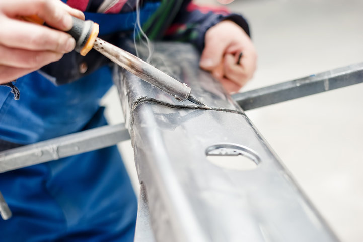 Automotive engineer working on car and using a plastic welder