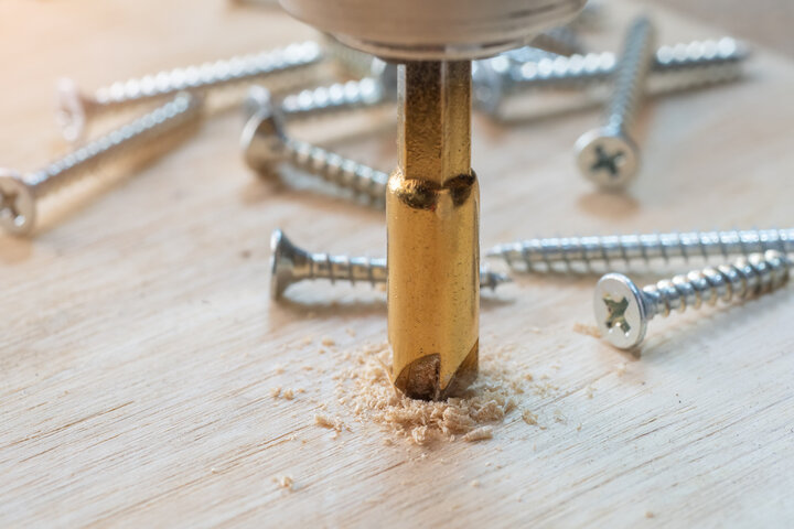 Carpenter use countersink bit to drill both a pilot hole and use countersink bit to recess the head of the screw into wood plank